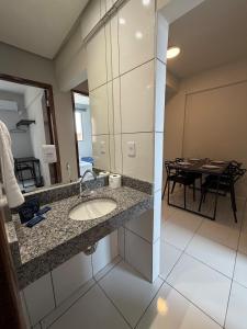 a bathroom with a sink and a dining table at Apto com 2 quartos e A/C ao lado da Santa Casa in Montes Claros