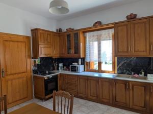 a kitchen with wooden cabinets and a window at Georgia House Portaria in Portaria