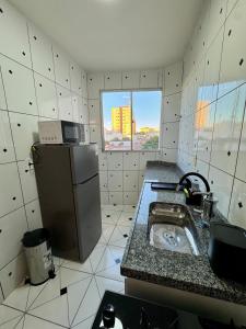 a small kitchen with a sink and a refrigerator at Apto com 2 quartos e A/C no Centro in Montes Claros