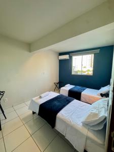 two beds in a room with a blue wall at Apto com 2 quartos e A/C no Centro in Montes Claros
