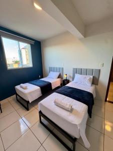 a bedroom with two beds and a window at Apto com 2 quartos e A/C no Centro in Montes Claros +27 photos