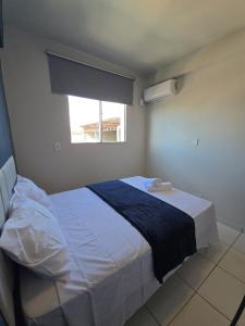 a bedroom with a large white bed with a window at Apto com 2 quartos e A/C no Centro in Montes Claros +34 photos