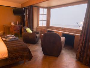 een hotelkamer met een bed en stoelen en een raam bij Hotel Villa Escale in De Panne