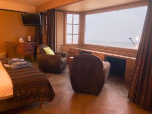 ein Hotelzimmer mit einem Bett, Stühlen und einem Fenster in der Unterkunft Hotel Villa Escale in De Panne