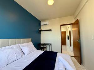 a bedroom with a white bed and a blue wall at Apto com 2 quartos e A/C no Centro in Montes Claros