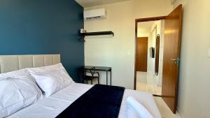 a bedroom with a bed and a door to a bathroom at Apto com 2 quartos e A/C no Centro in Montes Claros