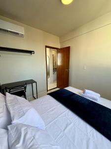 a bedroom with a large white bed and a desk at Apto com 2 quartos e A/C no Centro in Montes Claros +36 photos