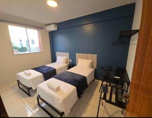 a bedroom with two beds and a blue wall at Apto com 2 quartos e A/C no Centro in Montes Claros