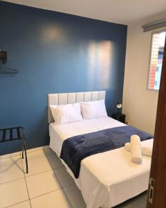 a bedroom with a large bed with a blue wall at Apto com 2 quartos e A/C no Centro in Montes Claros