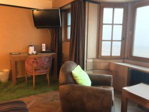a hotel room with a chair and a desk and a television at Hotel Villa Escale in De Panne