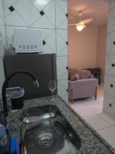 a kitchen with a sink and a living room with a couch at Apto com 2 quartos e A/C no Centro in Montes Claros