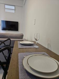 a dining room table with plates and a wine glass at Apto com 2 quartos e A/C no Centro in Montes Claros