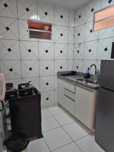 a kitchen with a black and white tiled wall at Apto com 2 quartos e A/C no Centro in Montes Claros +28 photos