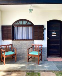 two wooden chairs sitting in front of a house at Apartmento102 - Condomínio Brisa Mar in Cabo Frio