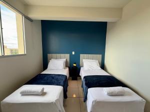 two beds in a room with blue walls at Apto com 2 quartos e A/C no Centro in Montes Claros