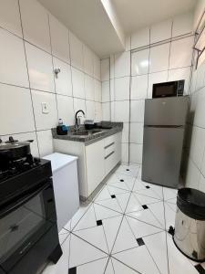 a kitchen with white appliances and a black and white tile floor at Apto com 2 quartos e A/C no Centro in Montes Claros