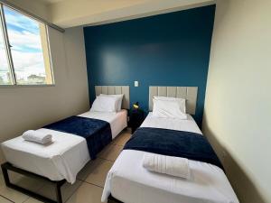 two beds in a room with blue walls at Apto com 2 quartos e A/C no Centro in Montes Claros +53 photos