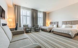 a hotel room with two beds and a couch at Hotel Montfort in Nicolet