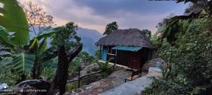 a small hut with a thatched roof on a mountain at The Cloud door in Perumālmalai