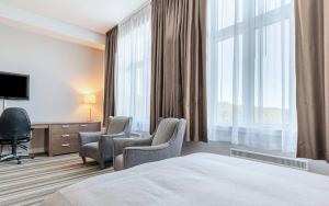 a hotel room with two chairs and a bed and a television at Hotel Montfort in Nicolet