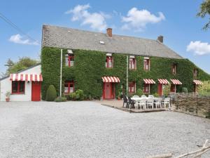 a building covered in green ivy with tables and chairs at Ferme de la Galoperie in Couvin