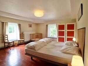 a large bed in a room with two windows at La Dépendance du Château in Huy