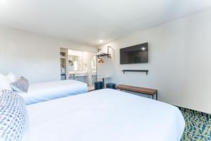 a bedroom with two beds and a tv at The Grove at Pismo Beach in Pismo Beach