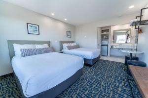 a hotel room with two beds and a table at The Grove at Pismo Beach in Pismo Beach