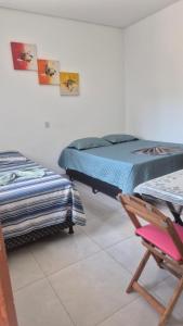 two beds in a room with a chair and a chair at Lindo APTO bem localizado em Sinop! in Sinop