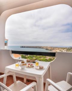 a table with food and drinks and a view of the ocean at Aparthotel Navigator in Sagres