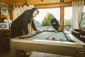 two people playing pool on a pool table at Chalet Hotel Alpaka in Châtel