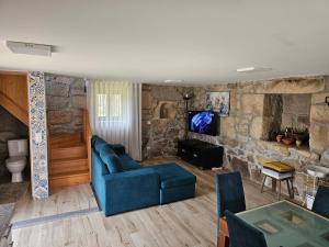 a living room with a blue couch and a stone wall at Quinta da Cachada in Lousada