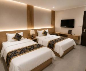 a hotel room with two beds and a flat screen tv at An Bình Luxury Hotel in Bắc Giang