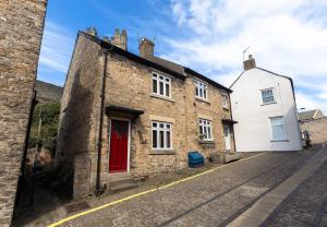 an old brick building with a red door on a street at JACKS COTTAGE - Cosy Cottage in the Heart of Richmond in Richmond