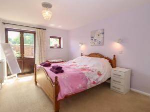 a bedroom with a pink bed and a window at Lowbrook Cottage in Diss