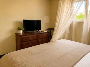 a bedroom with a bed and a television on a dresser at Rancho el Sobrino in Sabana Westpunt