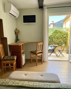 a living room with a television and a desk and chairs at Lou Mistral - chambres de charme climatisées, centre historique in Moustiers-Sainte-Marie