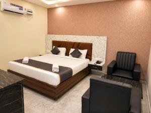 a bedroom with a large bed and a chair at Hotel GVR Prime in Guntūr