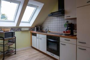 a kitchen with white cabinets and a sink and two windows at Ferienwohnung STEUERMANN in Werdum in Werdum