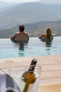 a man and woman sitting in a swimming pool at Casa do Paço Suítes Douro Valley in Peso da Régua