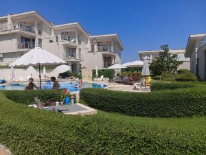 a hotel with a pool with people sitting under an umbrella at Sun Village House 14 in Byala