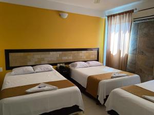 ein Hotelzimmer mit zwei Betten und einem Fenster in der Unterkunft Hotel John David in Palenque