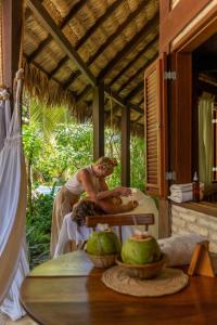 a man sitting on a table on a porch at Casa Fufi in Jericoacoara