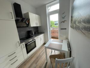 eine Küche mit weißen Schränken, einem Tisch und einem Fenster in der Unterkunft Brigg in Emden