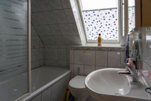 a bathroom with a sink and a tub and a toilet at Ferienwohnung SCHIFFSJUNGE in Werdum in Werdum