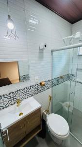 a bathroom with a toilet and a sink and a shower at Suíte Excellence - 02 in Pirenópolis