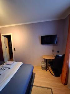a bedroom with a bed and a desk and a television at Stadtrand Hotel in Hagen