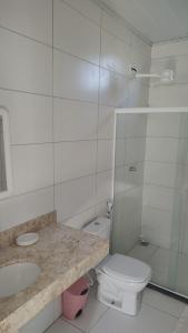 a white bathroom with a toilet and a sink at Casa Verde in Morro de São Paulo