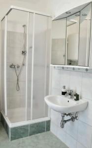 a white bathroom with a sink and a shower at Historic Flat & Private Courtyard in Bruck an der Leitha