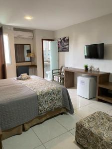 a bedroom with a bed and a desk and a television at Serra Negra Pousada Spa - by Easy Hotéis in Guarapari